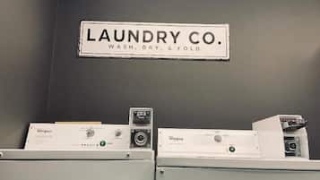 A laundry area with two Whirlpool washers and a sign above them that reads "LAUNDRY CO. WASH, DRY, & FOLD."