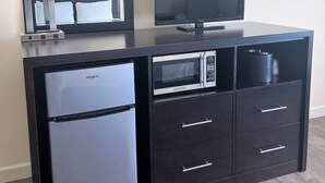 A compact kitchenette with a refrigerator, microwave, and a flat-screen TV on a dark cabinet. - University Inn Durham next to Duke University Medical Center (Durham)