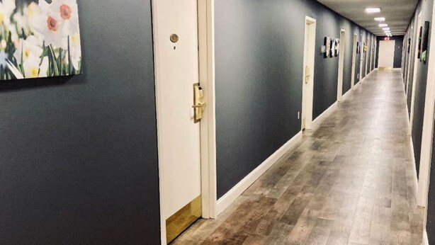 A long, narrow hallway with dark walls and wooden flooring. - University Inn Durham next to Duke University Medical Center (Durham)