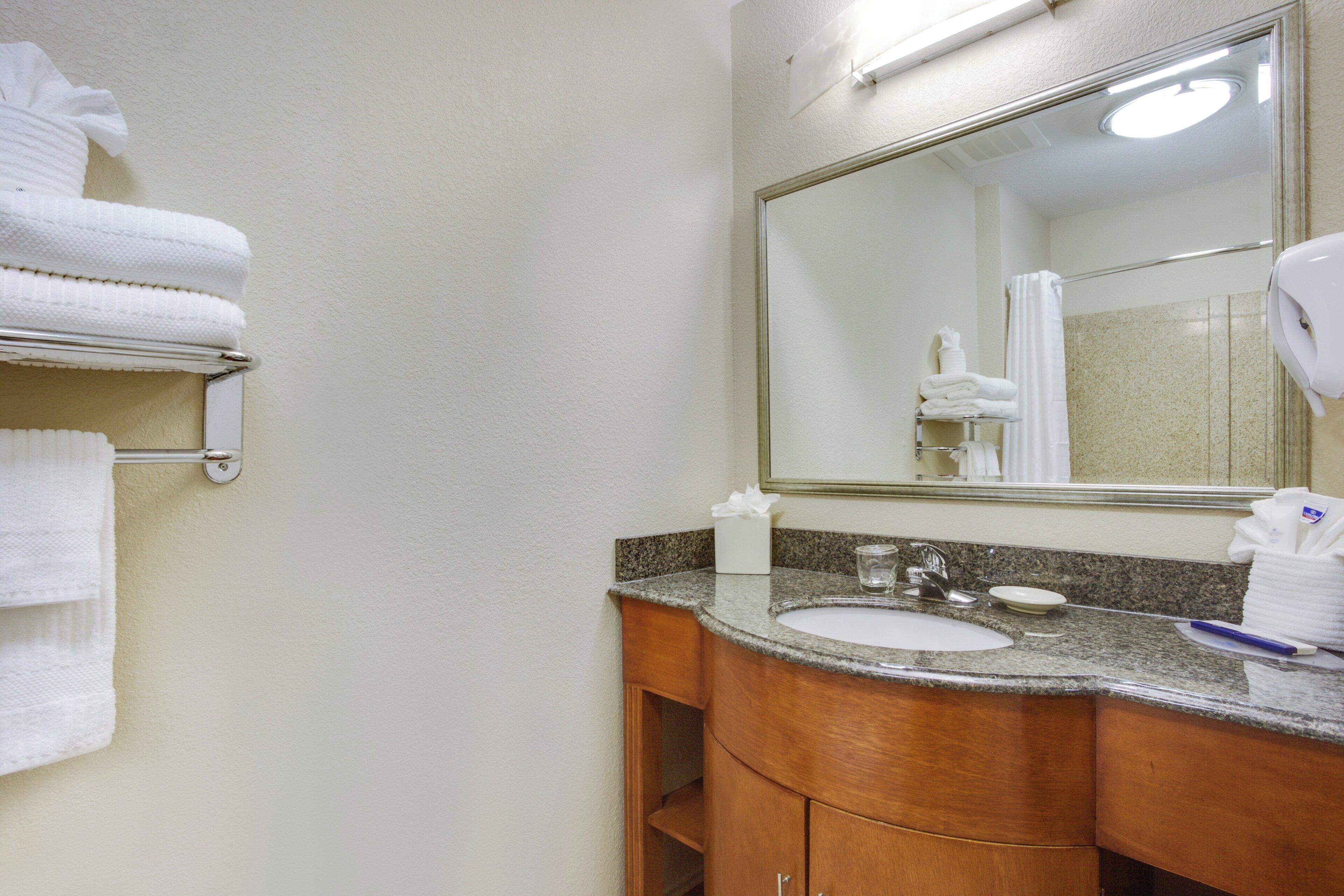 A bathroom with a sink, mirror, towel rack, and a hand dryer.