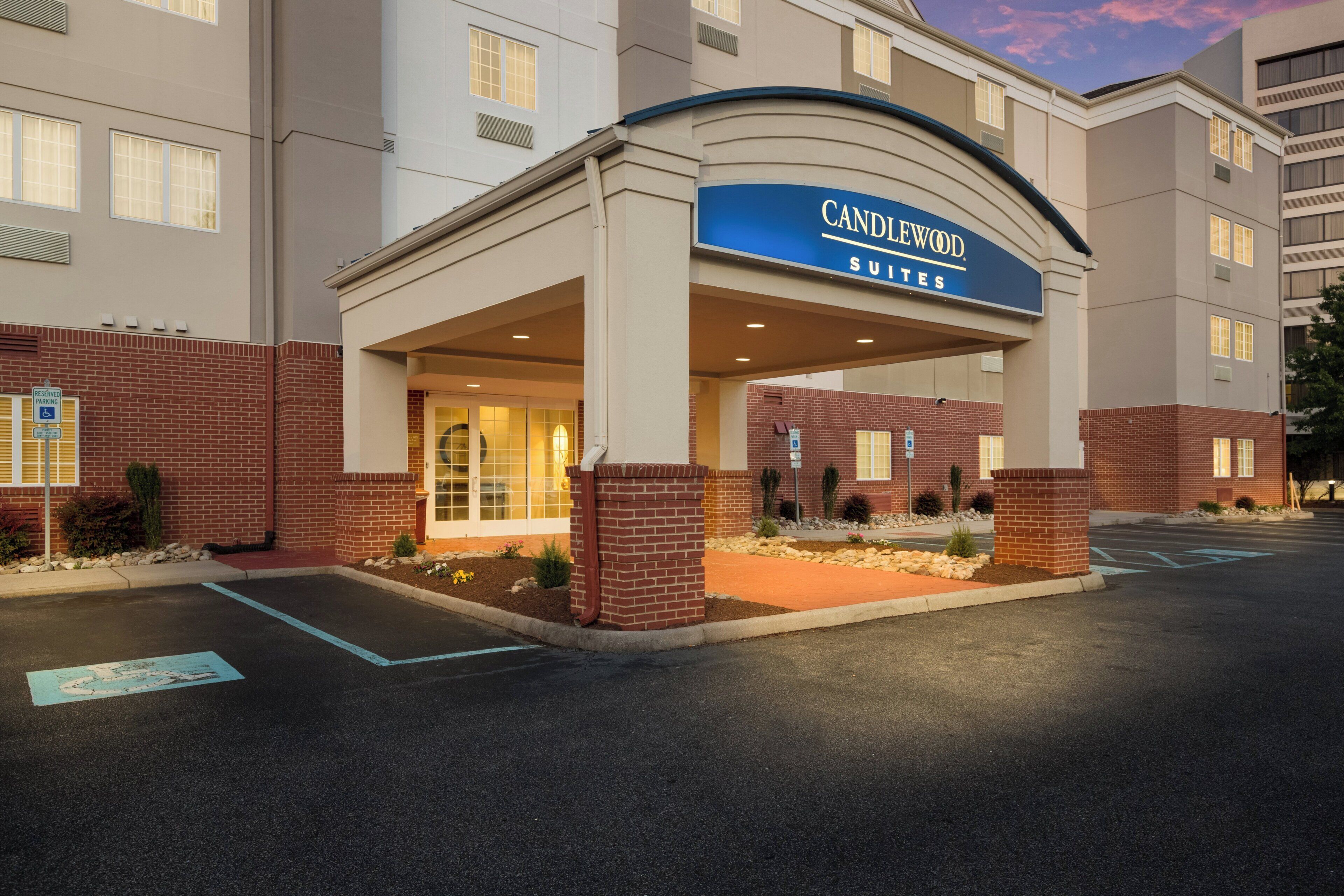 L’entrée de l’hôtel Canindow Suites se distingue par sa façade en briques, un espace d’entrée abrité et un parking.