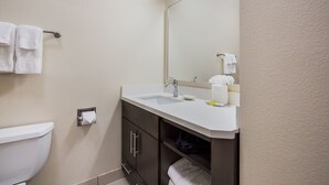 A bathroom with a toilet, sink, mirror, and towel rack. - Candlewood Suites Virginia Beach Town Center by IHG (Virginia Beach)