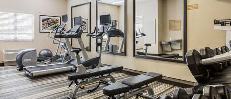 Un gimnasio con cintas de correr, elípticas, bancos y mancuernas.