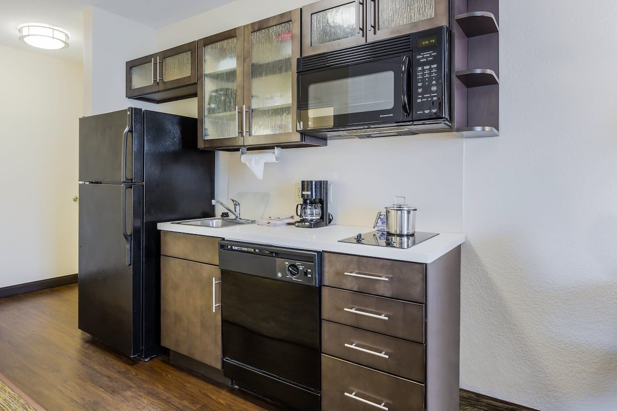 Una cocina moderna con un refrigerador negro, un lavavajillas, un microondas y una cafetera.