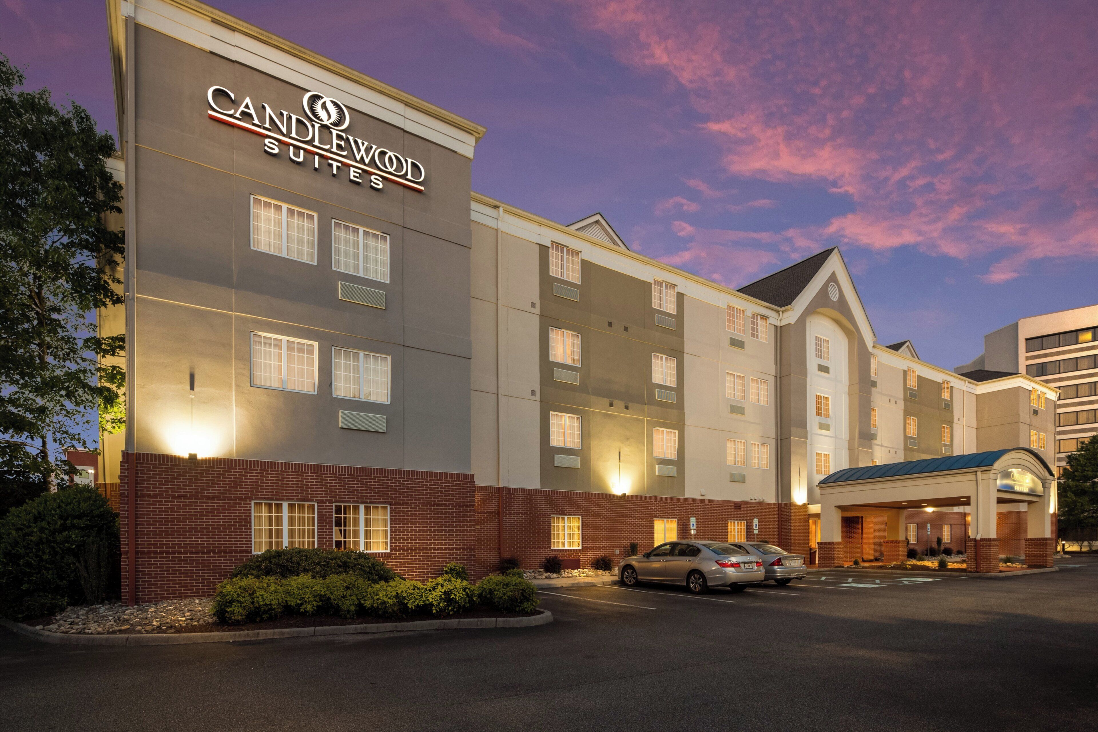 A hotel with a modern facade, multiple windows, and a parking area.