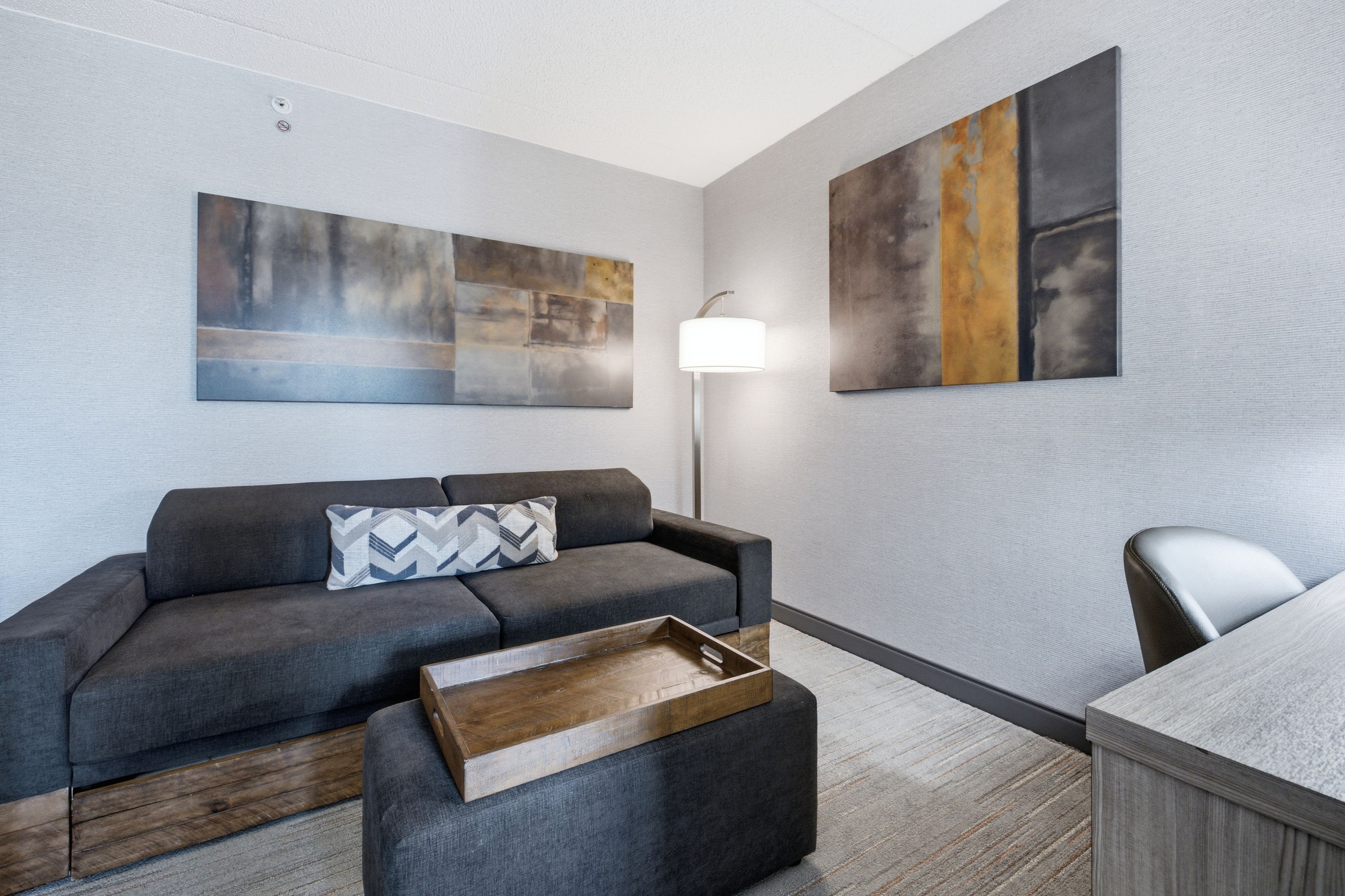 A modern living room with a grey sofa, a wooden coffee table, and a lamp.