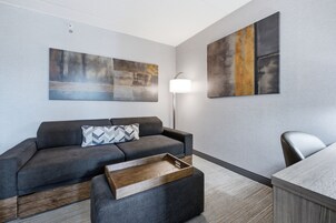 Una sala de estar moderna con un sofá gris, una mesa de centro de madera y una lámpara.