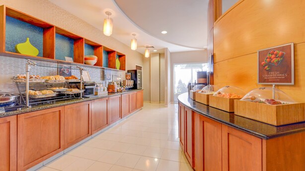 A breakfast bar with various food items and a sign for fresh strawberries.