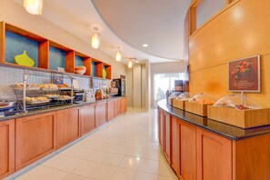 Una barra de desayuno con diversas opciones de comida y un letrero que anuncia fresas frescas.
