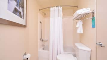 A bathroom with a toilet, bathtub, shower, and a towel rack.