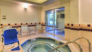 A pool area with a hot tub, chairs, and a view of the outdoors.