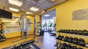 A gym with exercise equipment, dumbbells, and a treadmill.