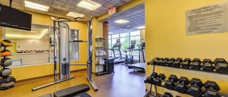 A gym with exercise equipment, dumbbells, and a treadmill.