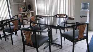 A dining area with a table and chairs, a water dispenser, and a television on the wall. - Loyalty Inn Rockingham (Rockingham)