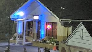 A building with a covered entrance, a neon sign, and a small garden area. - Loyalty Inn Rockingham (Rockingham)