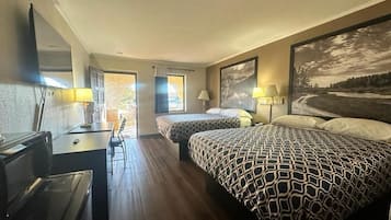 A hotel room with two beds, a desk, a chair, a mirror, and a large window.