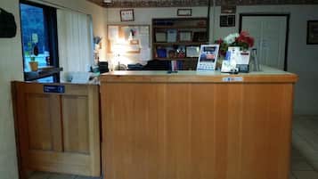 A reception desk with a wooden counter, a computer, and a sign with text.