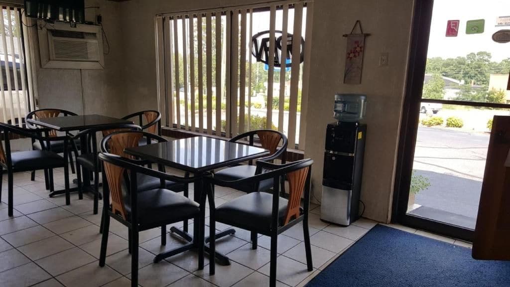 A restaurant interior with tables and chairs, a water dispenser, and a view of the outside.