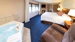 A hotel room with a large bed, a separate sofa, a fireplace, a TV, and a bathtub. - Hotel Glenwood Springs (Glenwood Springs)