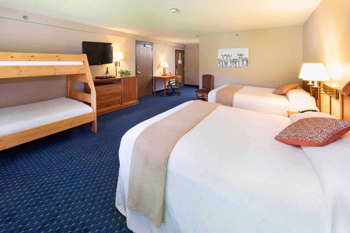 Ein Hotelzimmer mit zwei Betten, einem Schreibtisch, einem Stuhl, einem Fernseher und einer Tür.