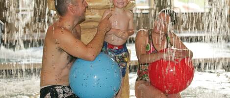 A man and a child in a water play area with a large water feature.