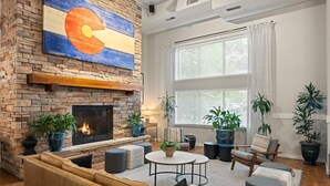 A cozy living room with a fireplace, comfortable seating, and large windows. - Hotel Glenwood Springs (Glenwood Springs)