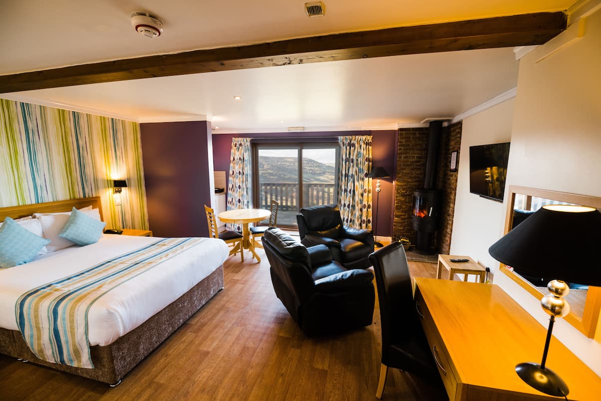 A hotel room with a bed, a massage chair, a desk, a chair, and a TV.