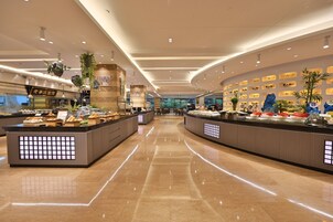 Un moderno vestíbulo de hotel con una recepción central, plantas decorativas y un piso de mármol pulido.