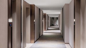 A long, narrow hotel corridor with a patterned carpet and wooden panel walls. - Crowne Plaza City Center Ningbo by IHG (Ningbo)