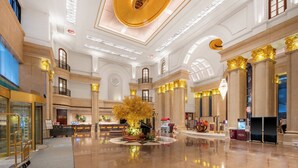 A spacious lobby with a central decorative tree, a reception desk, and a staircase leading to upper floors. - Crowne Plaza City Center Ningbo by IHG (Ningbo)