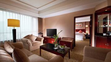 A hotel room with a sofa, a coffee table, a television, and a bed.