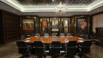 A conference room with a long table, black chairs, and framed artwork on the walls.