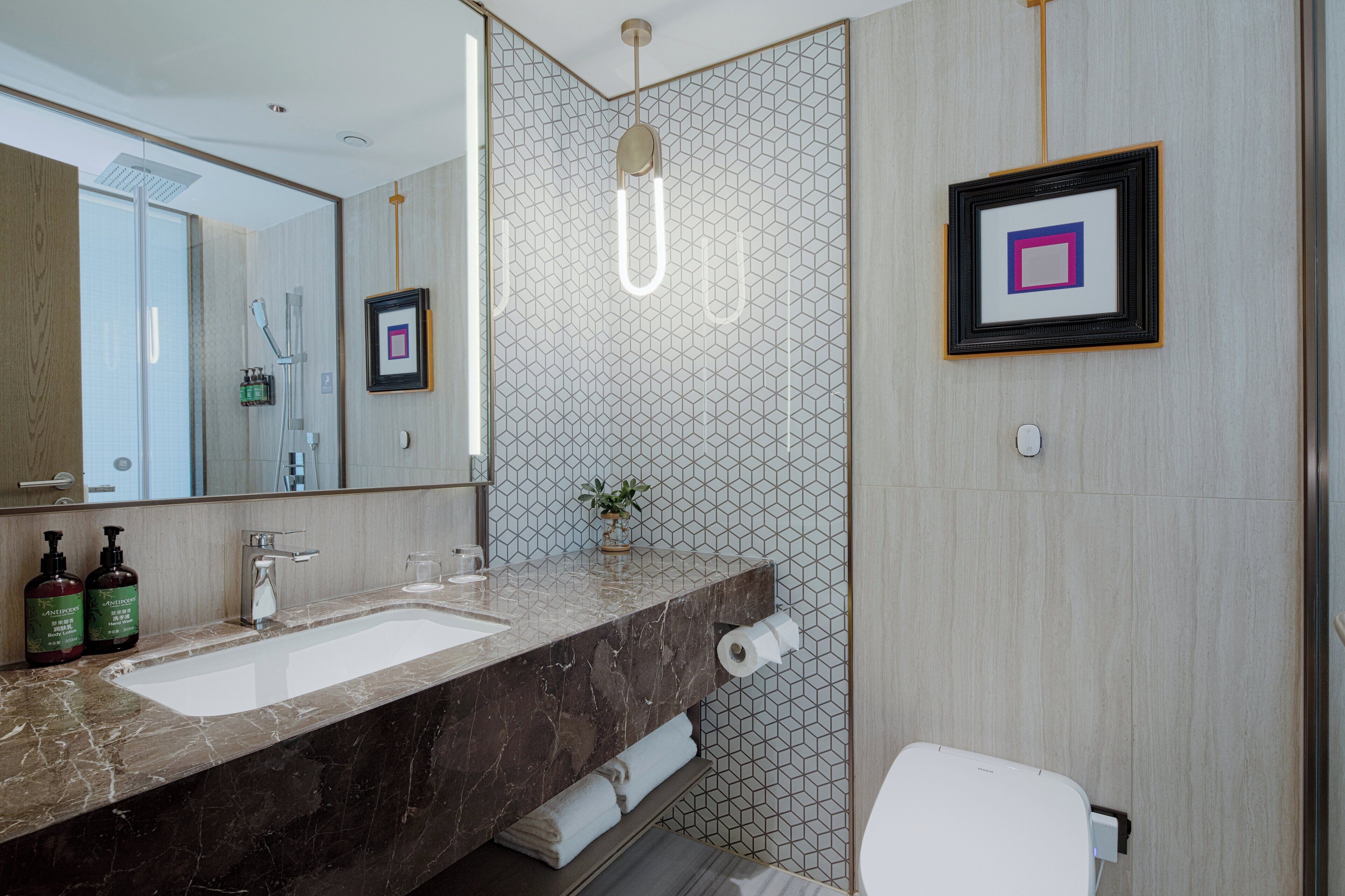 A modern bathroom with a marble sink, a large mirror, a shower, and a toilet.