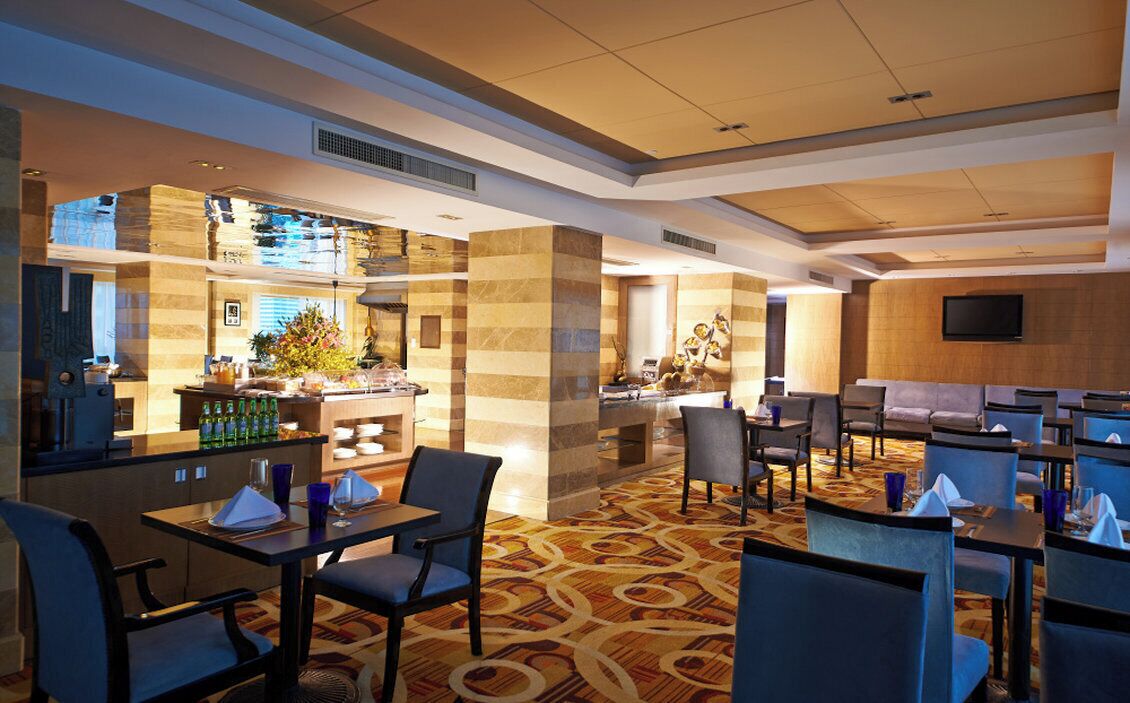 Un hall d’hôtel comprenant un bar, des espaces aménagés avec des sièges et un téléviseur fixé au mur.