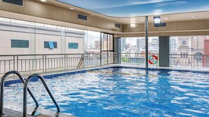 An indoor swimming pool with clear glass walls, a metal ladder, and a city view. - Crowne Plaza City Center Ningbo by IHG (Ningbo)