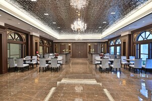 Eine großzügige Lobby mit hoher Decke, einem zentralen Chandelier und einem Marmorboden.