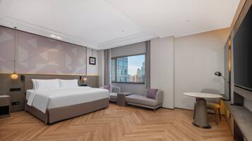 Una habitación de hotel moderna con una cama grande, un sofá, una mesita y un televisor.