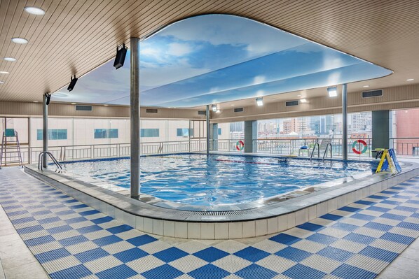 A swimming pool with a checkered floor, a lifeguard stand, and a view of the city through large windows. - Crowne Plaza City Center Ningbo by IHG (Ningbo)