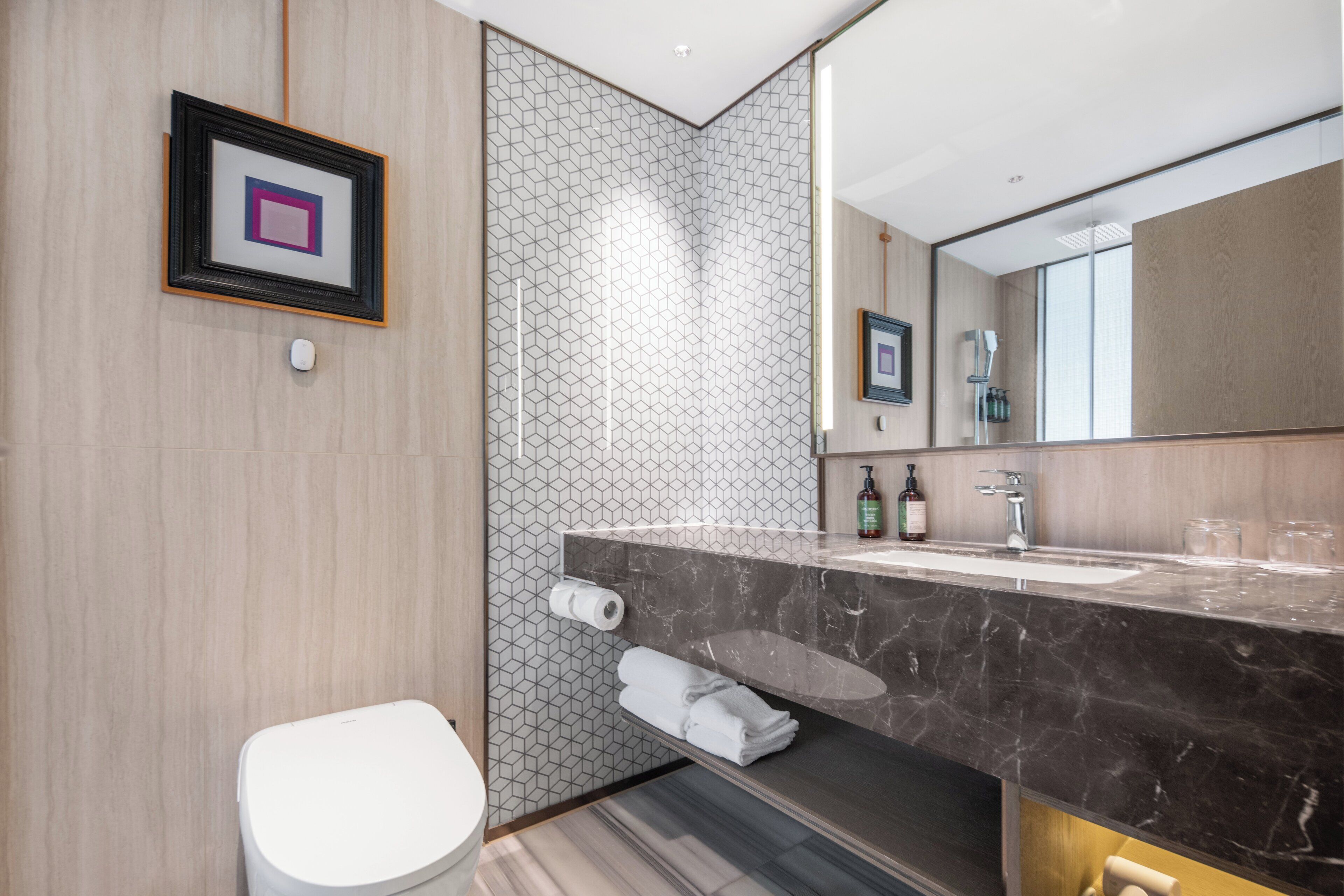 A modern bathroom with a marble sink, a toilet, and a towel rack.