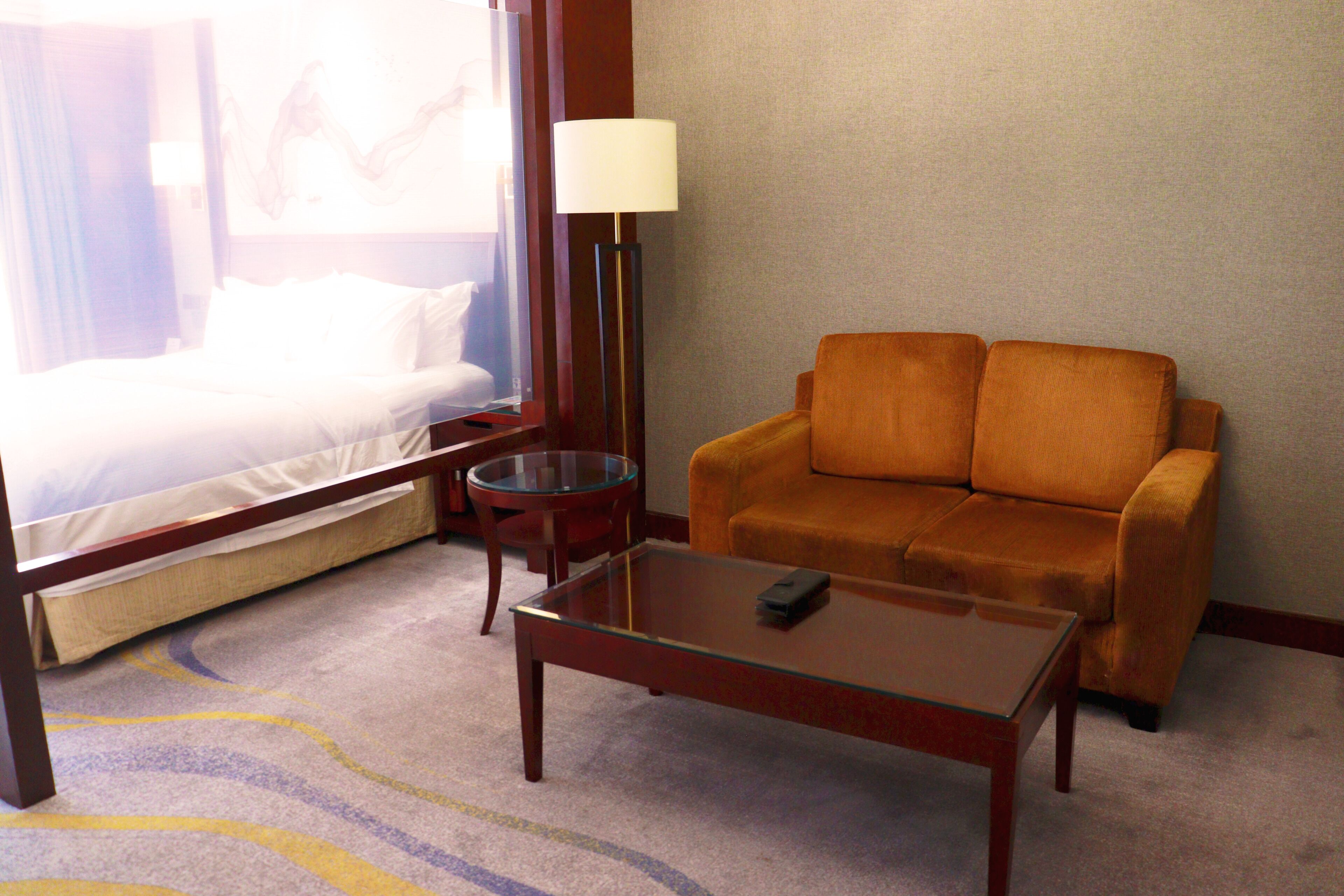 Una habitación de hotel con una cama, un sofá, una mesita y una lámpara.