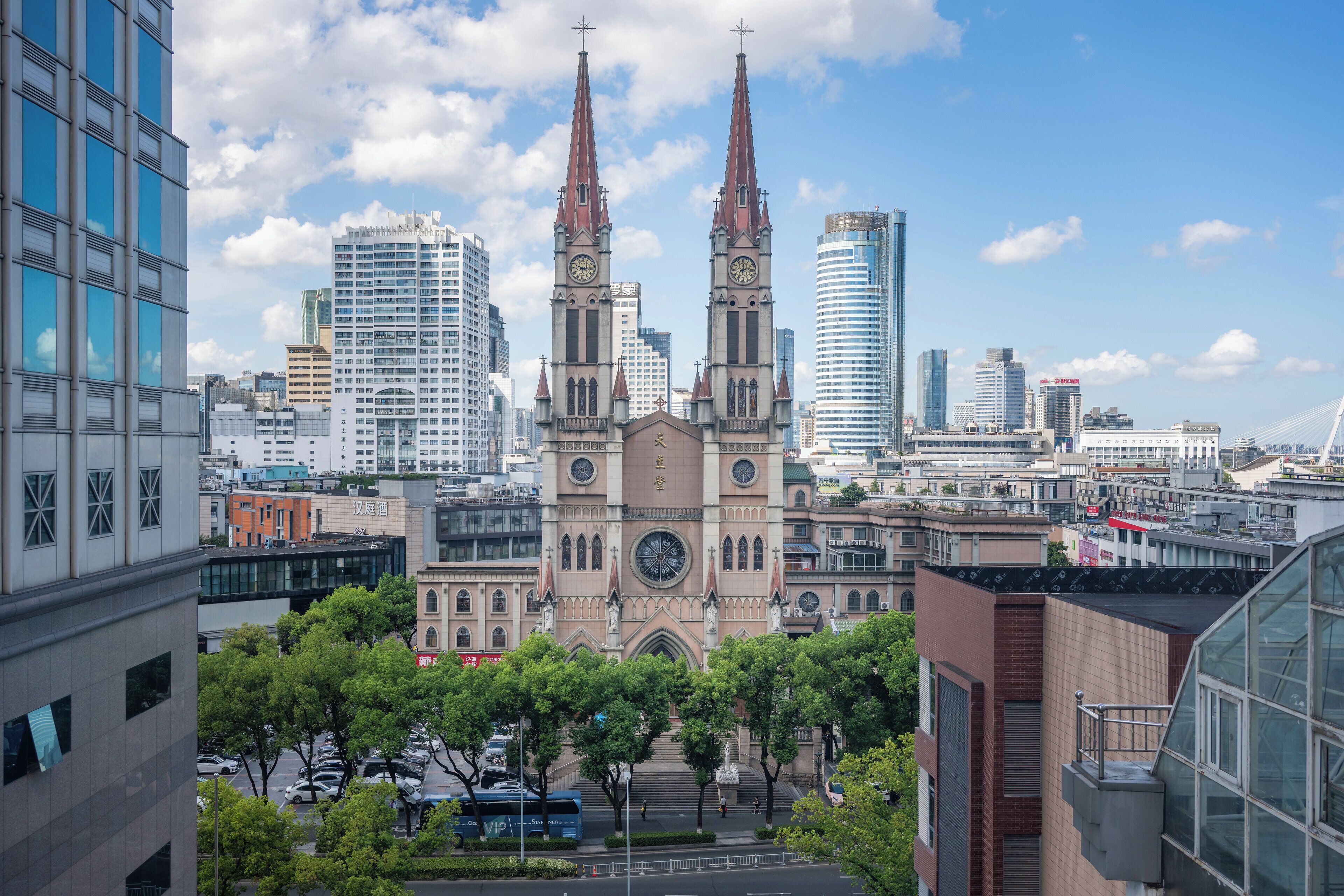 A cityscape with a prominent church featuring twin spires and a clock tower, surrounded by modern high-rise buildings.