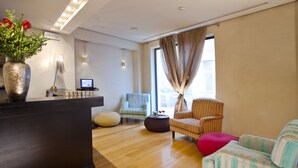 Un moderno vestíbulo de hotel con mostrador de recepción, zona de estar y grandes ventanales.