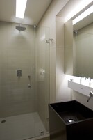 A modern bathroom with a glass-enclosed shower, a white sink, and a large mirror.