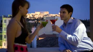 Una pareja sostiene copas de martini con vistas a un edificio histórico al fondo.