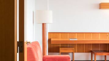 Una habitación moderna con un sofá rojo, una mesa de madera y una lámpara.