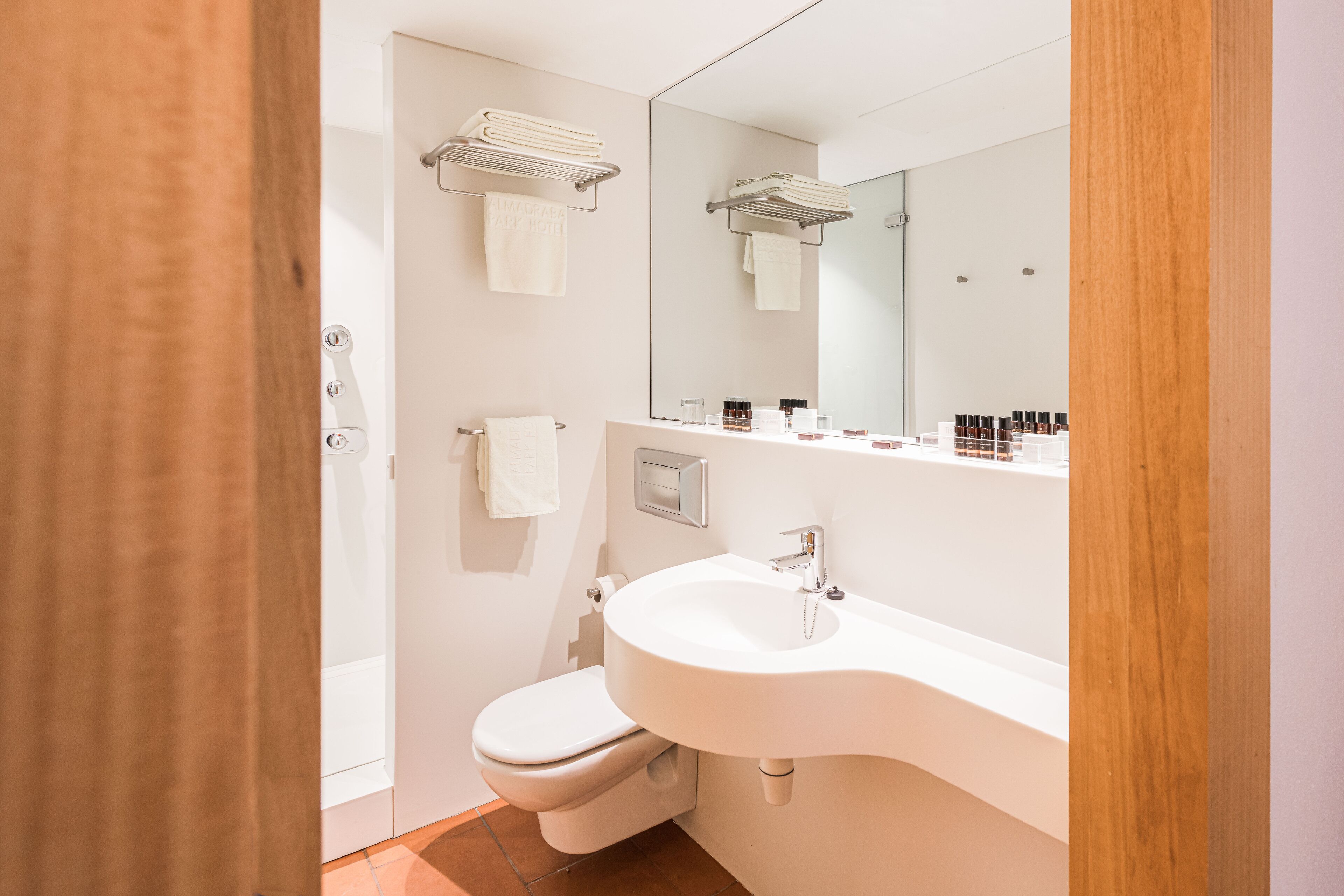 Een moderne badkamer met een wit wastafel, toilet en douche.