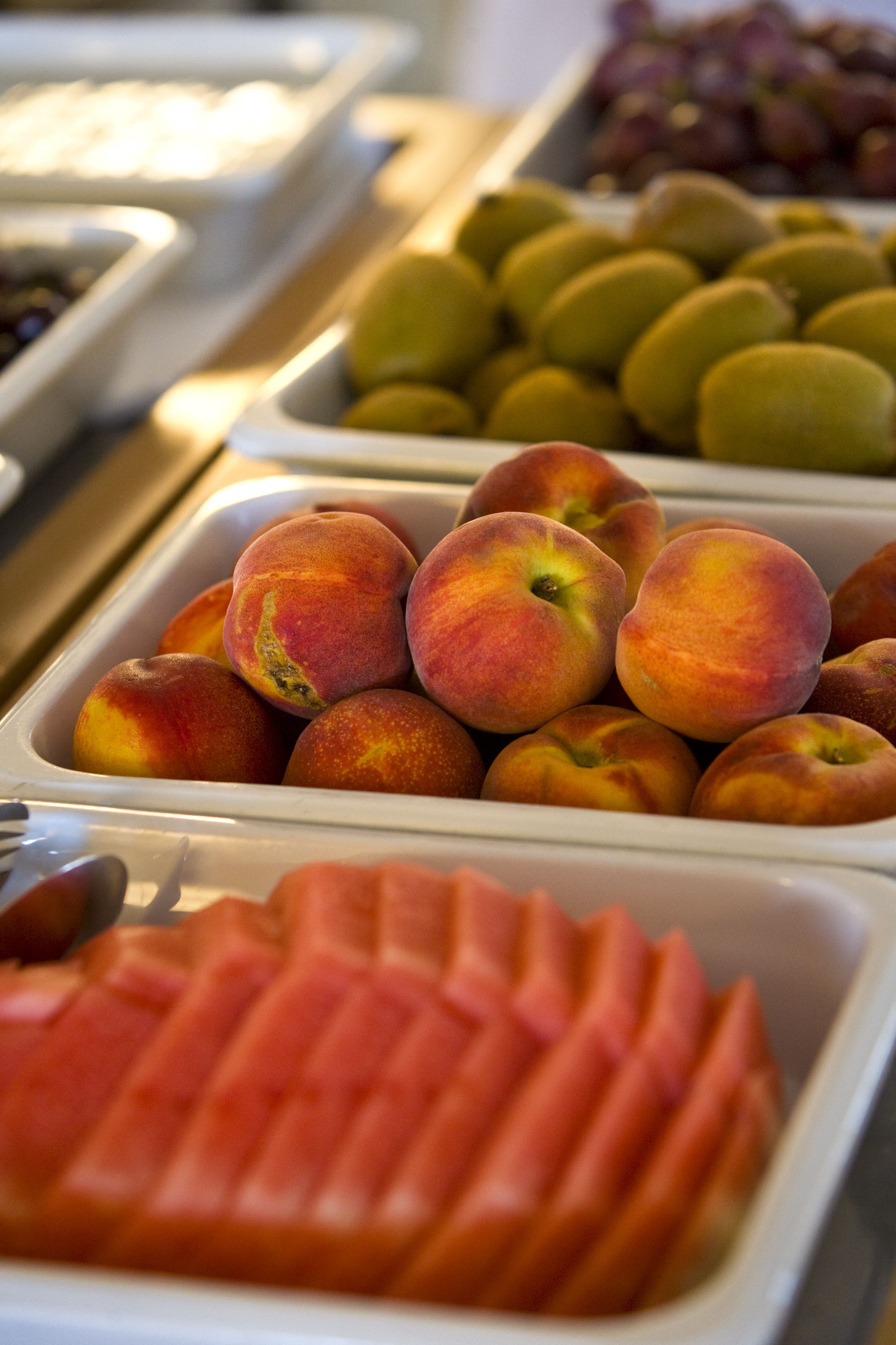 A buffet with various fruits including peaches and grapes.