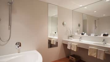 Een moderne badkamer met een badkuip, twee wastafels, een grote spiegel en een douche.
