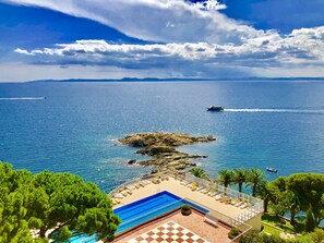 A coastal hotel with a swimming pool, a view of the sea, and a rocky outcrop. - Almadraba Park Hotel (Roses)