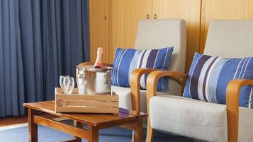Una habitación con una mesa de madera, dos sillones, un sofá y un armario de madera.